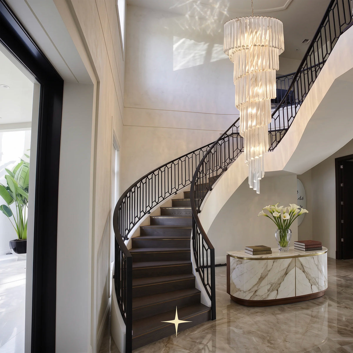 Bride glass spiral chandelier installed above a modern curved staircase in a luxury foyer
