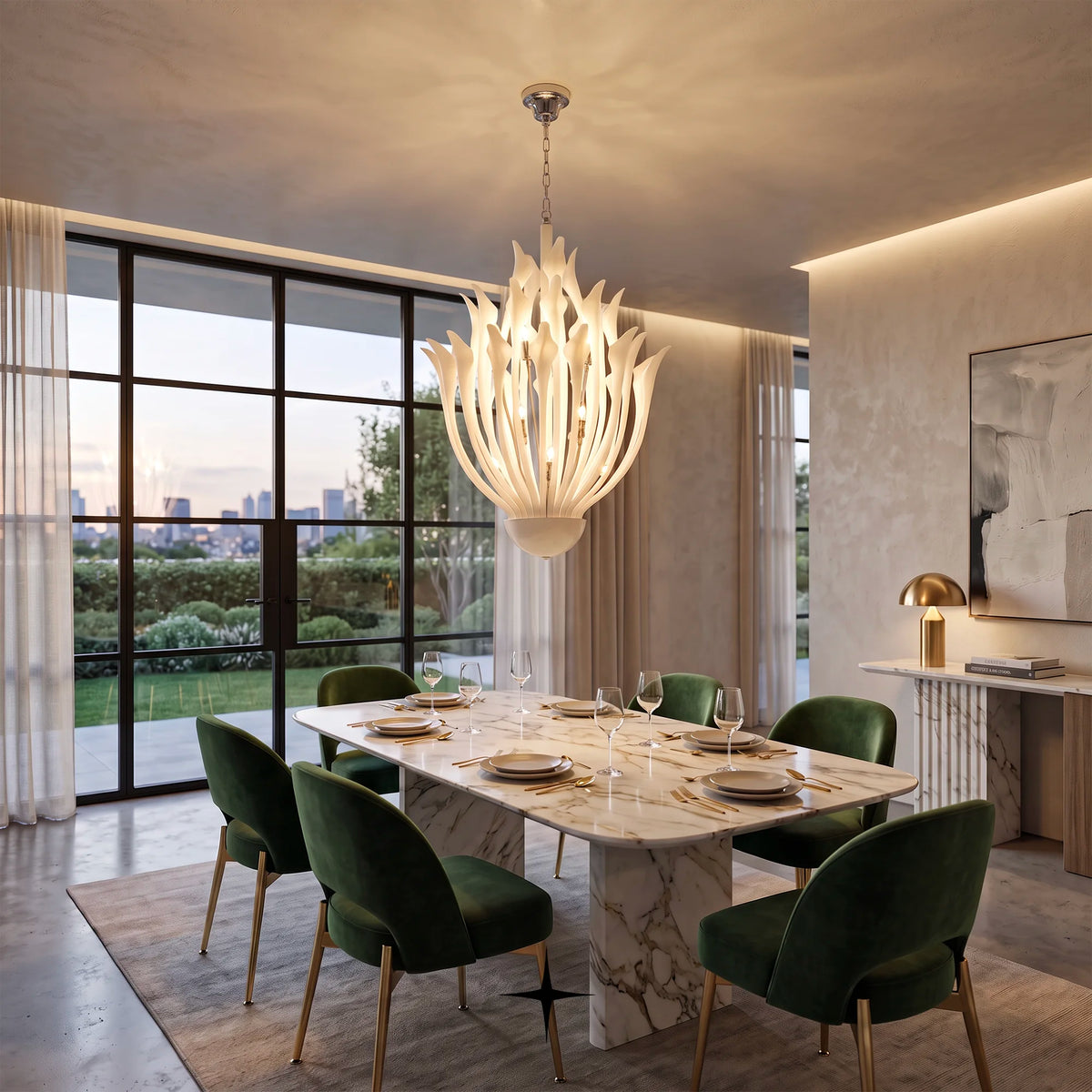 A modern dining room featuring a large, sculptural white candle-style chandelier hanging above a marble dining table with green velvet chairs. The room has a warm, elegant aesthetic with textured plaster walls, a large window looking out onto a garden at dusk, and a console table with a gold lamp.