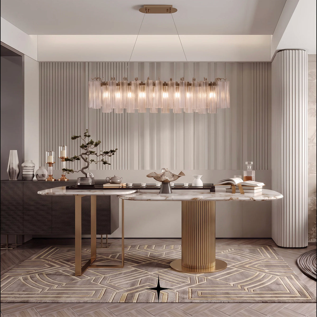 A modern dining room featuring a long rectangular marble-top table with a fluted gold pedestal base, a matching sideboard, a cylindrical astra crystal chandelier with clear glass tubes, and a geometric patterned rug.