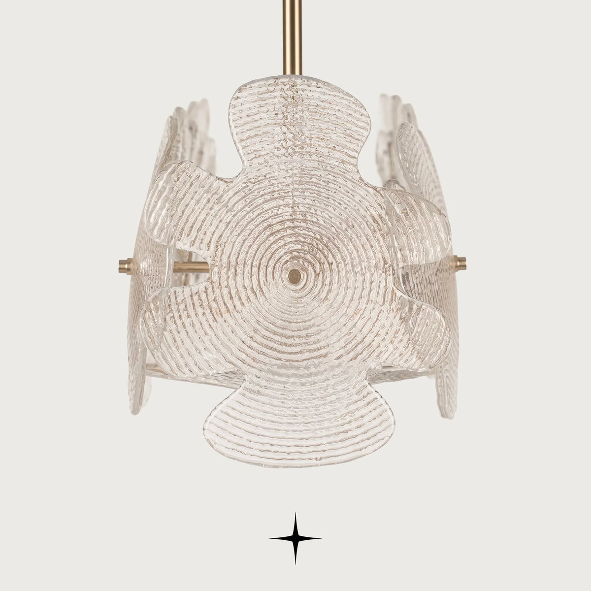 An abstract, sculptural nika light fixture made of textured, translucent glass petals with a brushed gold suspension rod, shown against a solid off-white background.