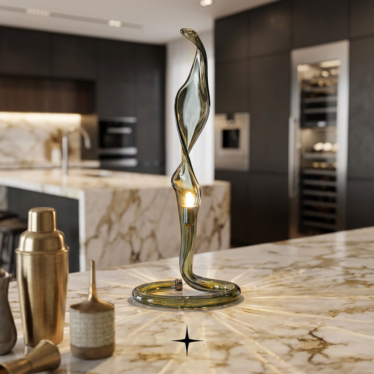 Veda modern sculptural fluid glass table lamp with metallic ring base table lamp with a warm light glowing from within, displayed on a marble kitchen island in a modern kitchen setting.