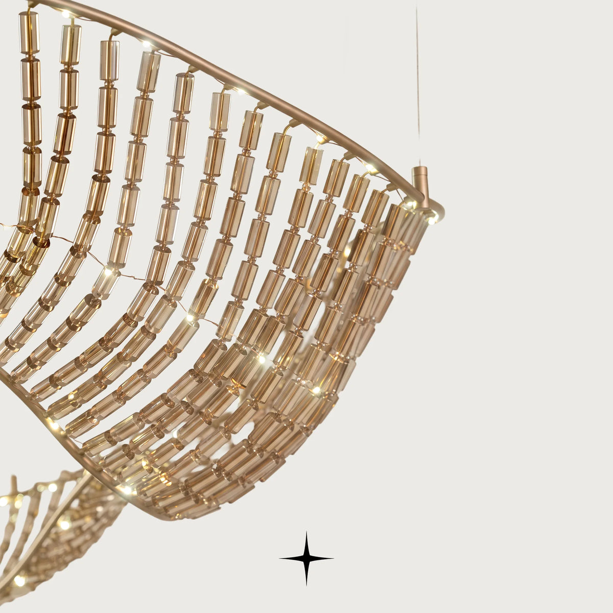 Close-up detail of golden metal structure and suspended crystals on Vortex chandelier