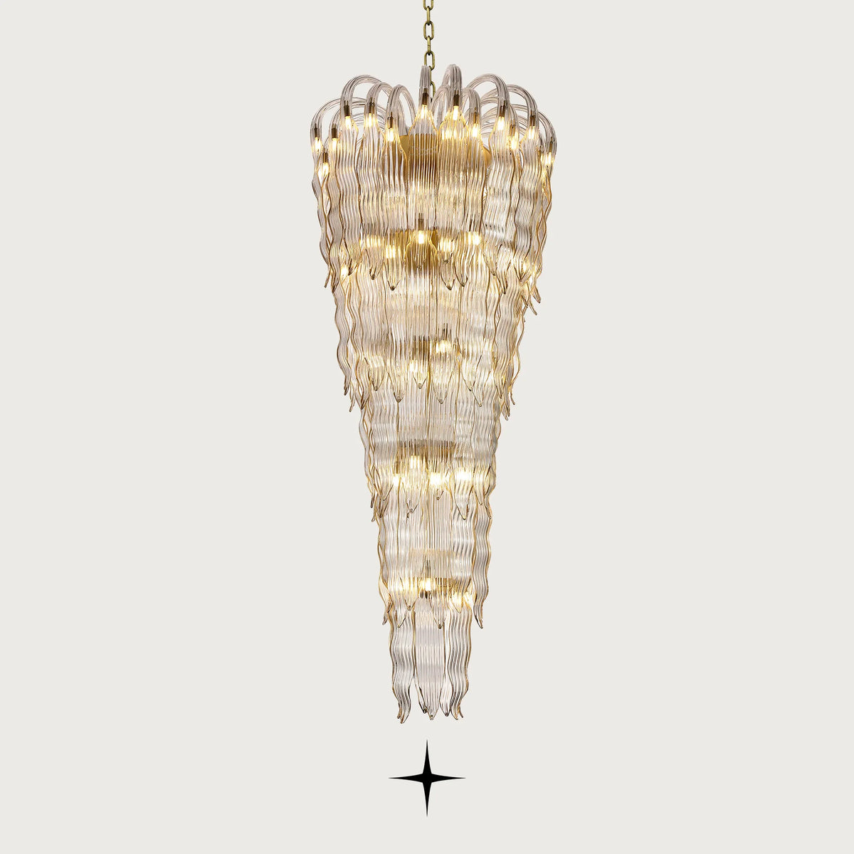 Grand Oriana multi-tiered cascading wave-glass waterfall chandelier illuminated on light grey background