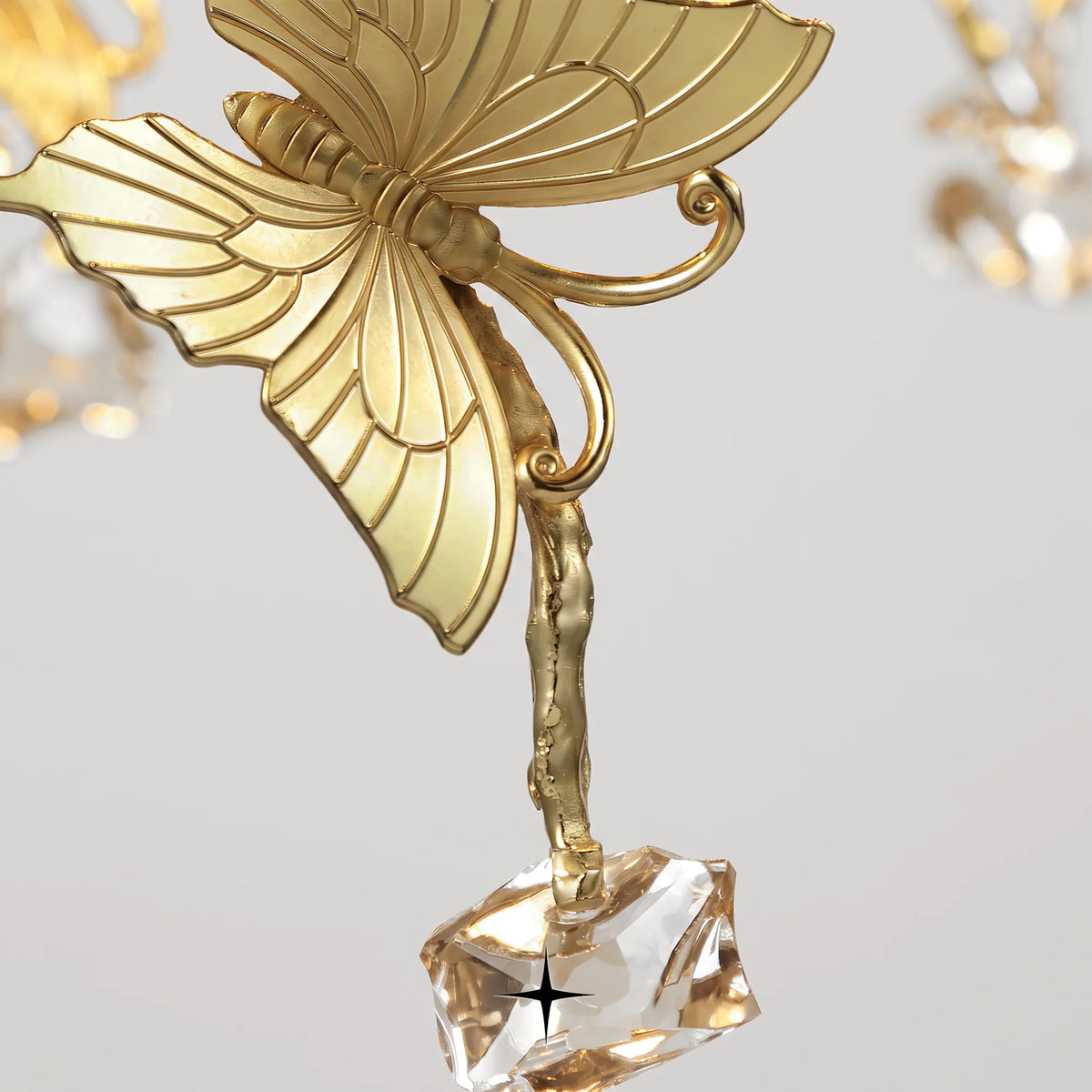 Detailed view of gold leaf butterfly and crystal elements on light grey background