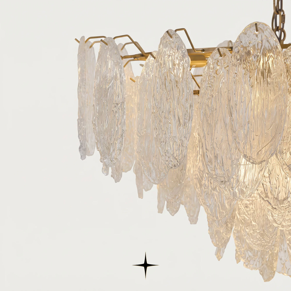 Close-up detail of warm brass structure and textured glass leaves on Saliva chandelier