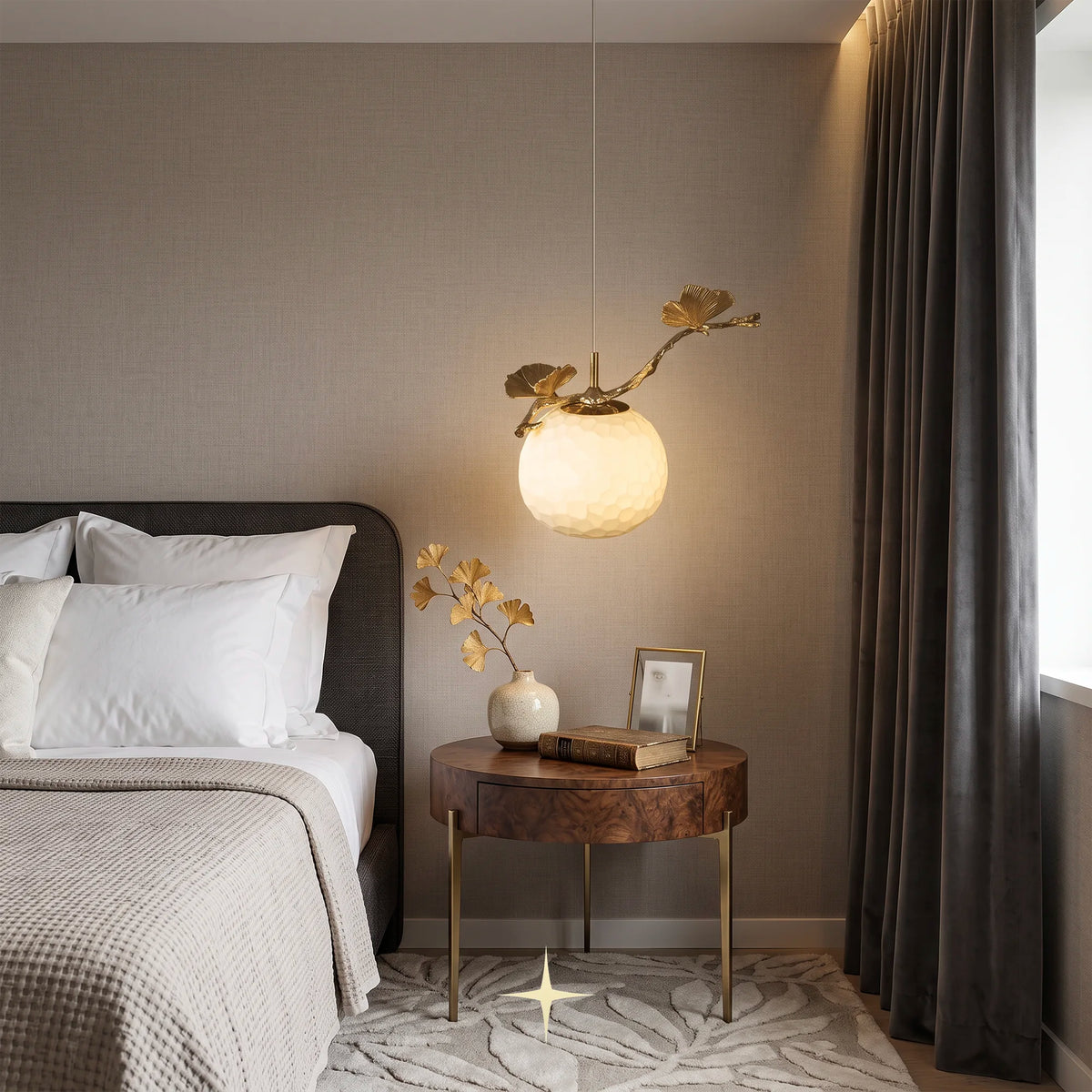 Warmly illuminated Zara pendant light hanging over a round wooden bedside table in a cozy bedroom setting